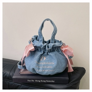 Détail du sac seau en jean avec nœuds en soie rose et broderies délicates