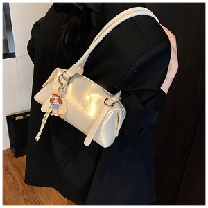 Detail of cream Boston bag with silver hardware and cute cartoon doll charm accessory