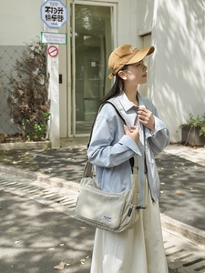 Detail of light grey nylon dumpling bag showing drawstring side pocket and branded label