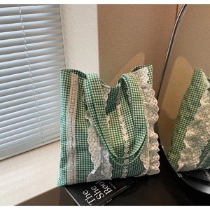 Close-up of green checkered tote bag featuring delicate white lace trim and canvas texture