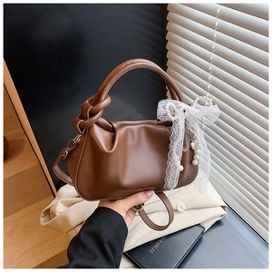 Detalle de bolso saco plisado marrón oscuro con lazo de encaje y colgante de perlas