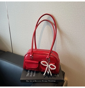 Close-up of red patent leather bowling bag with pearl bow and dual front pockets