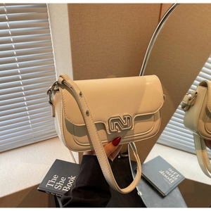Detail shot of a cream leather flap bag with a silver N-shaped metallic buckle detail