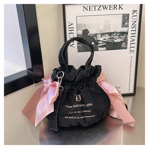 Détails du sac seau en denim noir avec nœuds en satin rose et broderie dorée