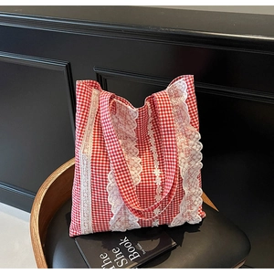 Detailed close-up of red and white gingham fabric with delicate white lace trim on a tote bag