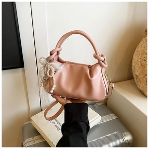 Detalle del bolso saco plisado rosa con colgante de encaje de perlas y asa anudada