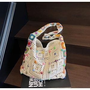 Détail d'un sac cabas en crochet ivoire avec des fleurs tricotées et des perles colorées