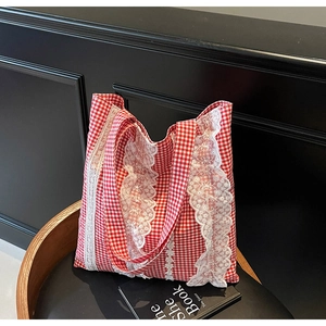 Detail of red and white checkered tote bag with elegant white lace trim on a chair