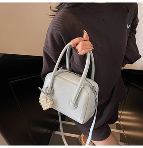 Close-up of light blue pillow bag with pearl heart charm and ribbon detail