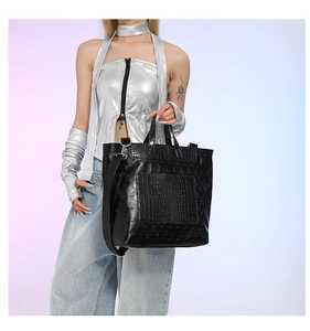 Detailed view of black tote bag featuring skull relief and crocodile texture on model
