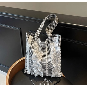 Detailed view of black and white checkered tote bag with lace trim and ruffled edges