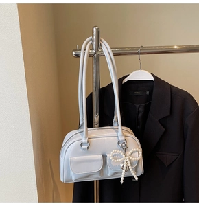 Detail of light blue glossy shoulder bag with twin pockets and pearl bow charm