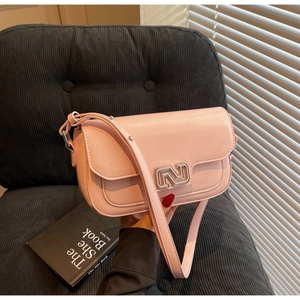 Detail view of pink leather crossbody bag with silver buckle on a corduroy chair