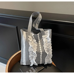 Close-up of black and white gingham tote bag featuring delicate white lace ruffle details