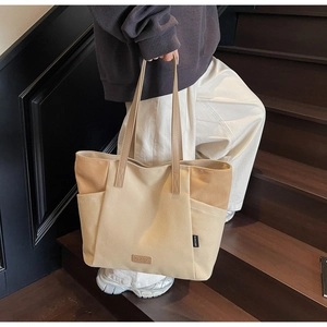 Detail van de grote canvas shopper met zijvak en beige lederen handvatstructuur