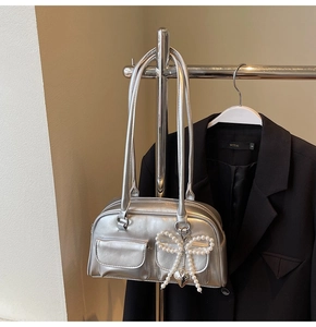 Detailed close-up of a silver Boston bag with double pockets and a pearl bow charm