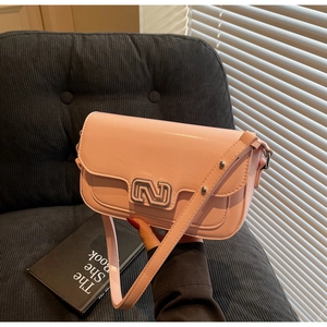 Detail of light pink crossbody bag with silver N-shaped buckle on a striped sofa