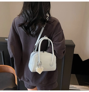 Detail of light blue patent leather handbag with pearl heart charm and shoulder strap