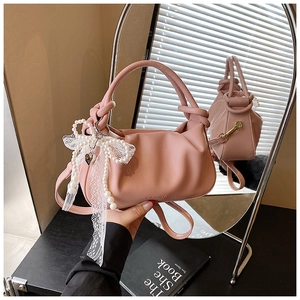 Detalle del bolso tipo saco plisado rosa con lazo de encaje perlado y asa anudada
