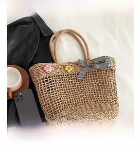 Detail of woven straw tote with 3D flowers and black-white checkered bow on fabric