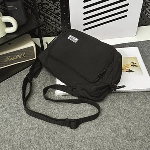 Close-up of black waterproof nylon dumpling bag with adjustable strap and front pocket
