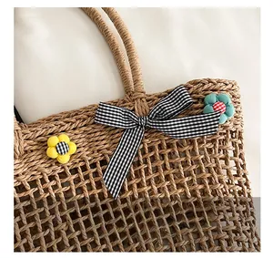 Close-up of hollow straw bag with checkered bow and fabric floral decorations