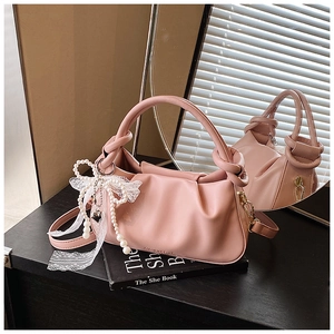 Detalle de bolso cubo plisado rosa con lazo de encaje, perlas y correa extraíble