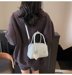 Close-up of light blue mini Boston bag with pearl heart charm and crossbody strap