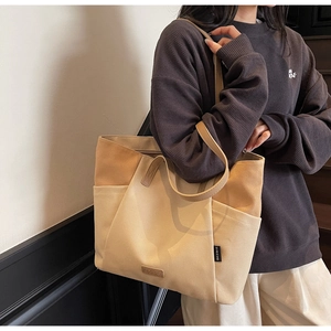 Detail van de tweekleurige canvas shopper met lederen merklogo en stevige handgreep