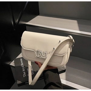 Detail of cream white leather handbag with silver N buckle on grey stairs