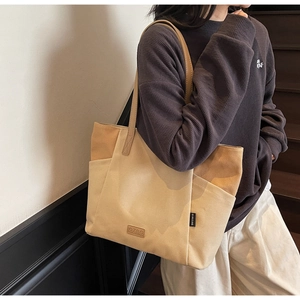 Detail van canvas tote bag met leren riemen en zijvak getoond op de schouder
