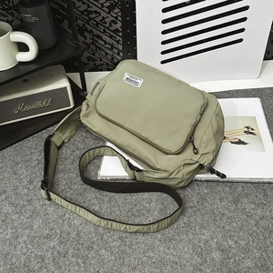 Olive green waterproof nylon crossbody dumpling bag displayed with urban lifestyle accessories