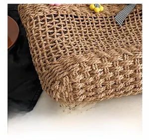 Detail of woven straw handbag featuring hollow mesh pattern and colorful floral ornaments