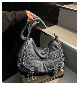 Detail of vintage blue denim hobo bag featuring silver buckles and double front pockets