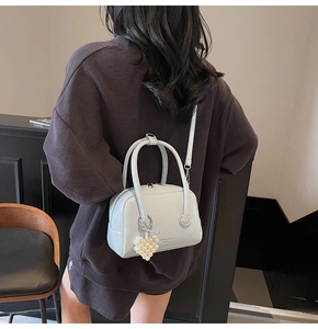 Detailed view of light blue leather satchel featuring a pearl heart charm on model