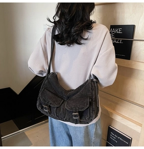 Detail shot of vintage dark grey denim crossbody bag with dual utility flap pockets