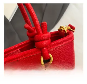 Detail of red lychee grain leather handle with knot design and gold metal hardware