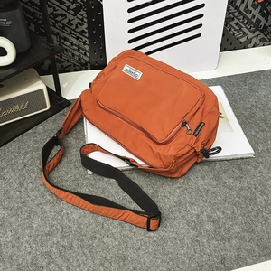 Detailed top view of a bright orange nylon crossbody bag with adjustable black shoulder strap