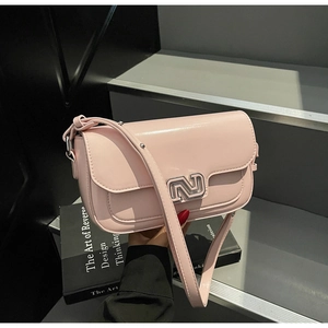 Detail of light pink faux leather shoulder bag with silver hardware on grey steps