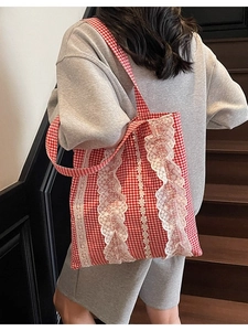 Red gingham tote bag with white floral lace trim shown on model at a wooden staircase