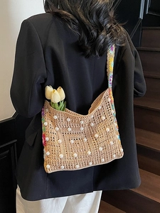 Sac bandoulière tissé avec perles et sangle bohème porté sur un blazer noir chic
