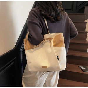 Detail van de canvas shopper met zijzakken en een hoogwaardig bruin leren merklogo-patch