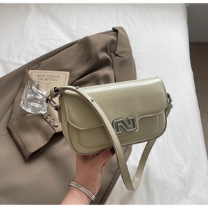 Detail of light green faux leather shoulder bag featuring a unique silver metal N-lock