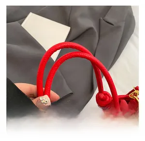 Close-up of red leather bucket bag featuring a thick handle and gold metal hardware