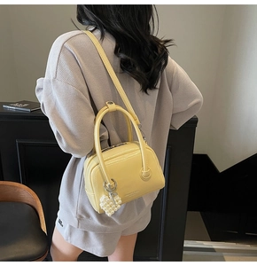 Detail shot of cream shoulder bag with pearl heart charm on a minimalist model