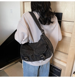 Detail of vintage black denim messenger bag with pockets shown from a back perspective
