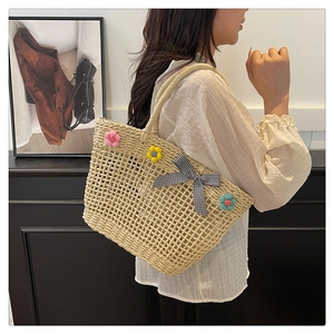 Detail of straw tote bag featuring colorful plush flowers and a gingham bow tie