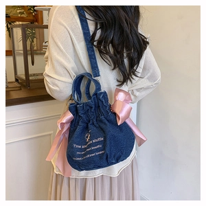 Détail du sac seau en jean avec des nœuds en satin rose et une broderie raffinée