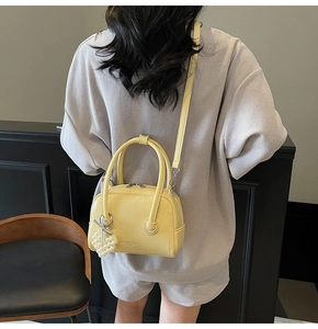 Detail of lemon yellow leather pillow bag with pearl bow charm on model