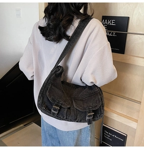 Rear view of black washed denim crossbody bag featuring dual flap pockets and buckles